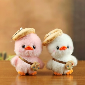 Detail of plush duck charms in pink and white with artist berets on wooden surface
