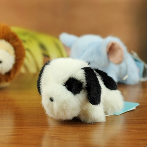 Close-up of a soft plush puppy puppet with black and white fur on a dark wooden surface