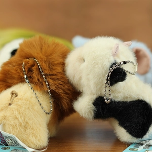 Detail of plush lion and cow keychains with bead chains and soft texture on wooden surface