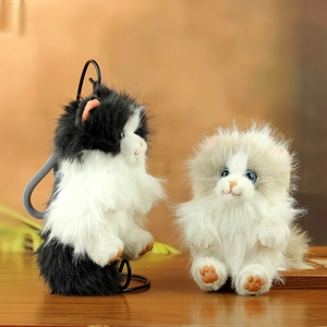 Realistic fluffy plush cat pendants in black and grey hanging on a metal stand