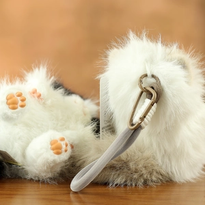 Close-up of plush cat keychain with white and brown faux fur and orange paw detail
