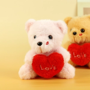 Detail of pink teddy bear plush with gold LOVE embroidery on a red heart