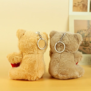 Detail view of the back of two soft plush teddy bear keychains in brown and grey colors