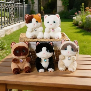 Set of five plush cat keychains with heart gemstone collars in a garden setting