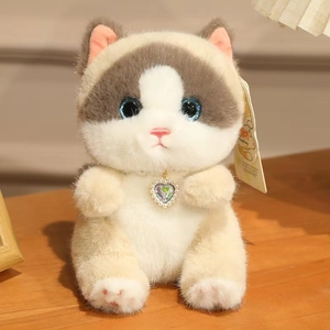 Detailed view of fluffy calico cat plush with blue eyes and heart pendant on wood surface