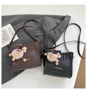 Detailansicht der gewebten Handtaschen in Schwarz und Braun mit Plüsch-Anhänger und Riemen