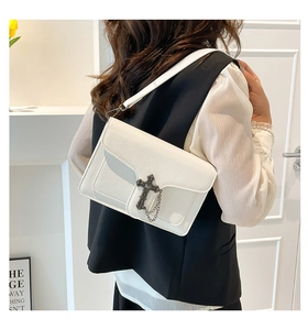 Detail of white lychee leather texture and cross metal buckle on stylish shoulder bag