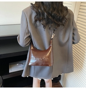 Detail of dark brown leather bucket bag with embossed logo and adjustable silver buckle