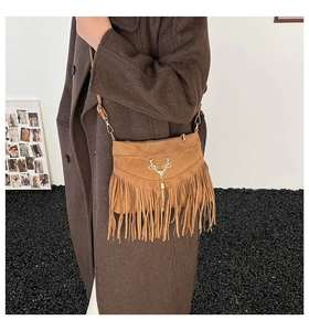 Sac bandoulière en daim marron avec boucle cerf dorée et long gland sur un mannequin