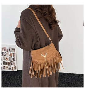 Détail d'un sac à bandoulière en daim marron avec cerf doré et franges bohèmes