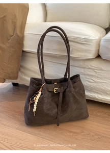 Close-up of retro brown faux suede tote bag with gold buckle and beaded tassel detail