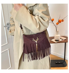 Détail du sac bandoulière en daim marron foncé avec boucle tête de cerf dorée et franges