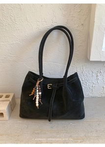 Detail of vintage black matte tote bag with golden buckle and wooden bead tassel decor