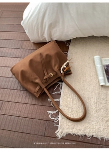 Close-up of brown suede tote bag featuring bohemian wood bead charm and golden buckle detail