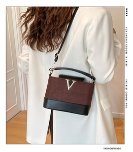 Detail view of the brown suede textured bag featuring a metallic V logo and stitching