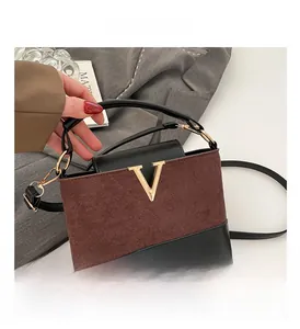 Close-up of a color-block bucket bag with a golden V emblem and brown suede texture
