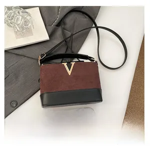 Detail of color-block vintage crossbody bag with gold V-buckle and suede texture