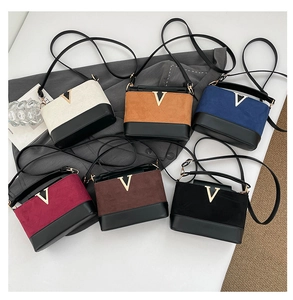 Flat lay of six colorblock crossbody bags in suede and leather with gold V-shape buckle