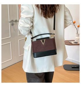 Détail du sac à bandoulière bicolore minimaliste avec boucle en métal V dorée et daim