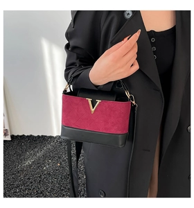Detailansicht der weinroten Wildledertasche mit goldenem V-Verschluss und Steppmuster