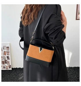 Detail einer Tasche mit Farblock-Design, goldenem V-Verschluss und Rautensteppung