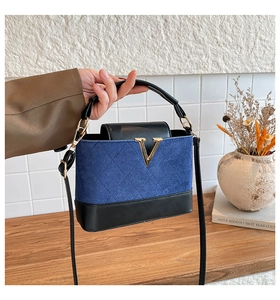 Detail der Handtasche aus blauem Wildleder und schwarzem Leder mit goldener V-Hardware