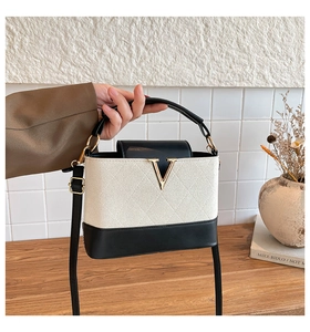 Detail der kleinen Farblock-Handtasche mit Steppmuster und goldenem V-förmigen Metall-Beschlag