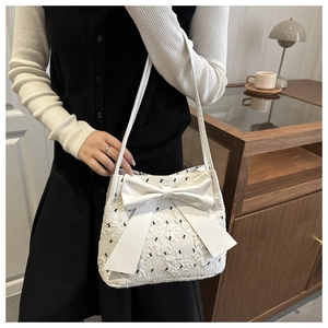 Detail of white seersucker tote bag with black patterns and large 3D bow accent