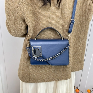 Elegante marineblauwe crossbodytas met gouden ketting en handvat op een model