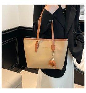 Detail van beige lederen shopper met olifantenhanger en Fashion & Bags tekstprint