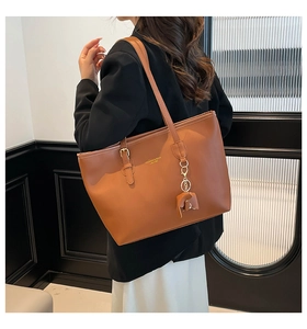 Brown leather tote bag featuring a cute elephant charm and premium gold logo detailing