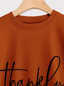 Detail of the caramel crewneck sweatshirt featuring black thankful script text print