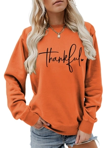 Close-up of orange sweatshirt with black Thankful script and heart print detail