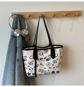Detailed view of the large-capacity tote bag with street style graffiti prints and black handles