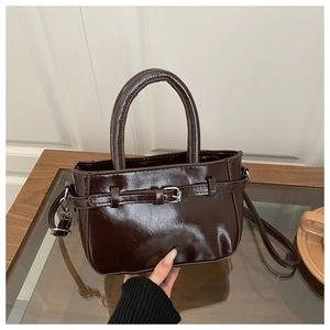 Detailed view of a vintage brown glossy handbag with decorative buckle and slim shoulder strap