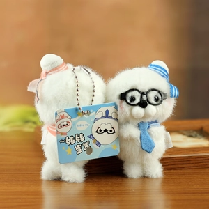 Detail view of plush white puppy pendants with bow and glasses on a wooden table