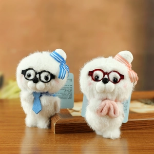 Pair of cute white plush seal pendants with striped hats and glasses on wood desk