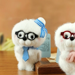 Close-up of cute white plush seal charm with round glasses and a blue striped hat