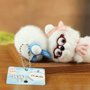 Detail of plush seal pendants with cute bows and glasses on a wooden tray