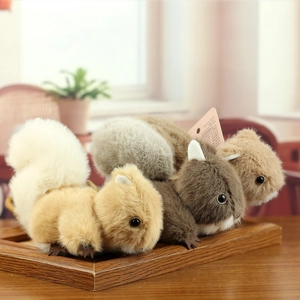 Détail de quatre porte-clés écureuils en peluche aux couleurs naturelles sur bois