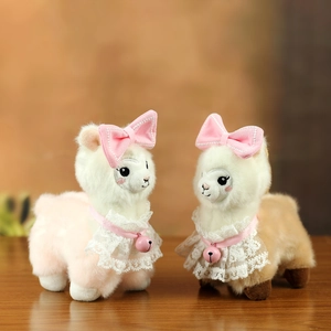 Cute alpaca plush keychain set with pink bows and lace collars on wooden surface