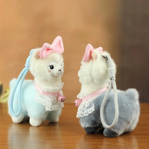 Detail of plush alpaca bag charm with pink bow, white lace collar, and ringing bell