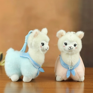 Close-up of cute plush alpaca charms with sailor collars and sequin stars on a wooden desk