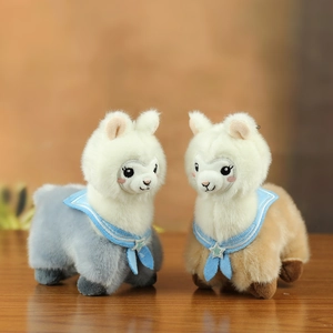 Detail of plush alpaca keychains with sailor collars and star sequins on a wooden table