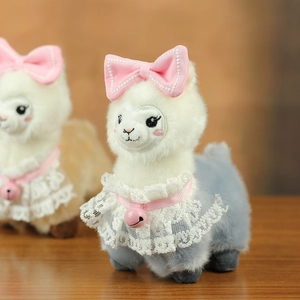 Close-up of cute alpaca plush with pink satin bow, lace collar and small bell detail