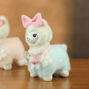 Detail of cute white plush alpaca wearing a blue coat with lace collar and pink bell