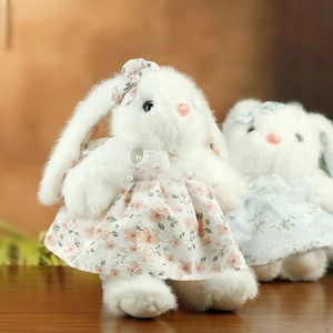 Dettaglio di simpatici conigli di peluche bianchi in abiti di pizzo floreale con perle