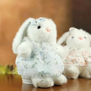 Dettaglio coniglio di peluche bianco con vestito di pizzo azzurro e collana di perle
