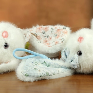 Dettaglio di un coniglio di peluche con pizzo delicato e motivi floreali rosa e verdi