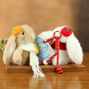 Detail of plush wedding bunny keychains with woven scarves and fruit hats hanging accessories